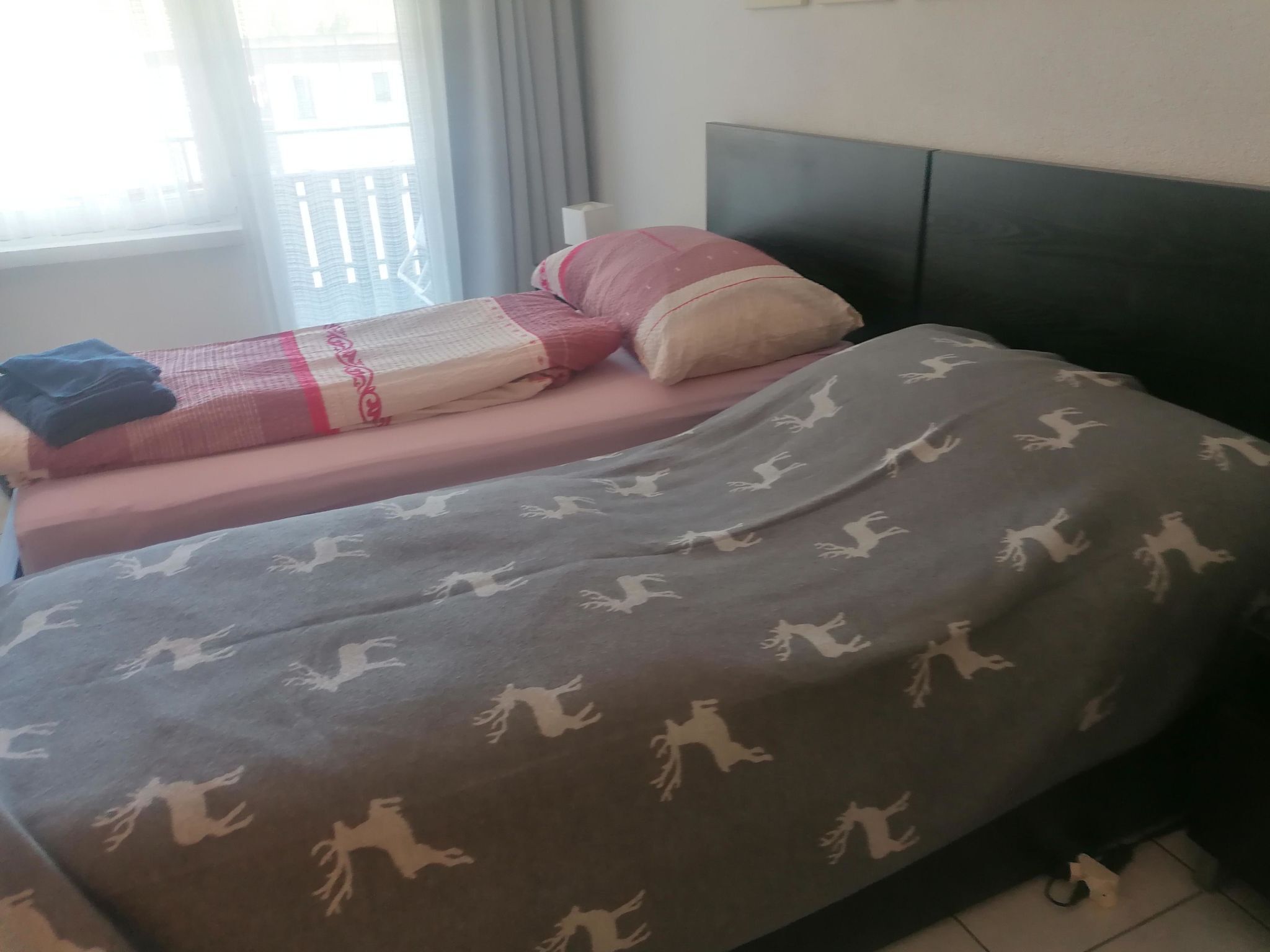 A bed with a patterned blanket, pillows, and a headboard.