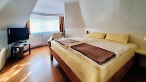 A room with a bed, a television on a stand, and a window with curtains.