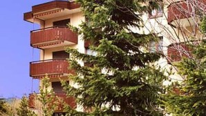 Un edificio de varios pisos con balcones, rodeado de follaje.