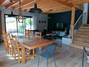 Ein geräumiger Wohnbereich mit einem Holzessttisch, Stühlen, einem Fernseher und einer Treppe.
