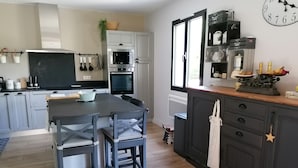 Ett modernt kök med en central köksö, inbyggd ugn, mikrovågsugn och en klocka på väggen.