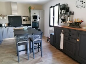 Eine moderne Küche mit einer zentralen Kochinsel, Backofen, Mikrowelle und einer Uhr an der Wand.