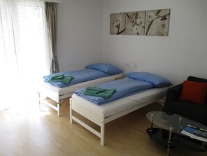 Ein Zimmer mit zwei Einzelbetten, einem kleinen Tisch und einem Sofa.