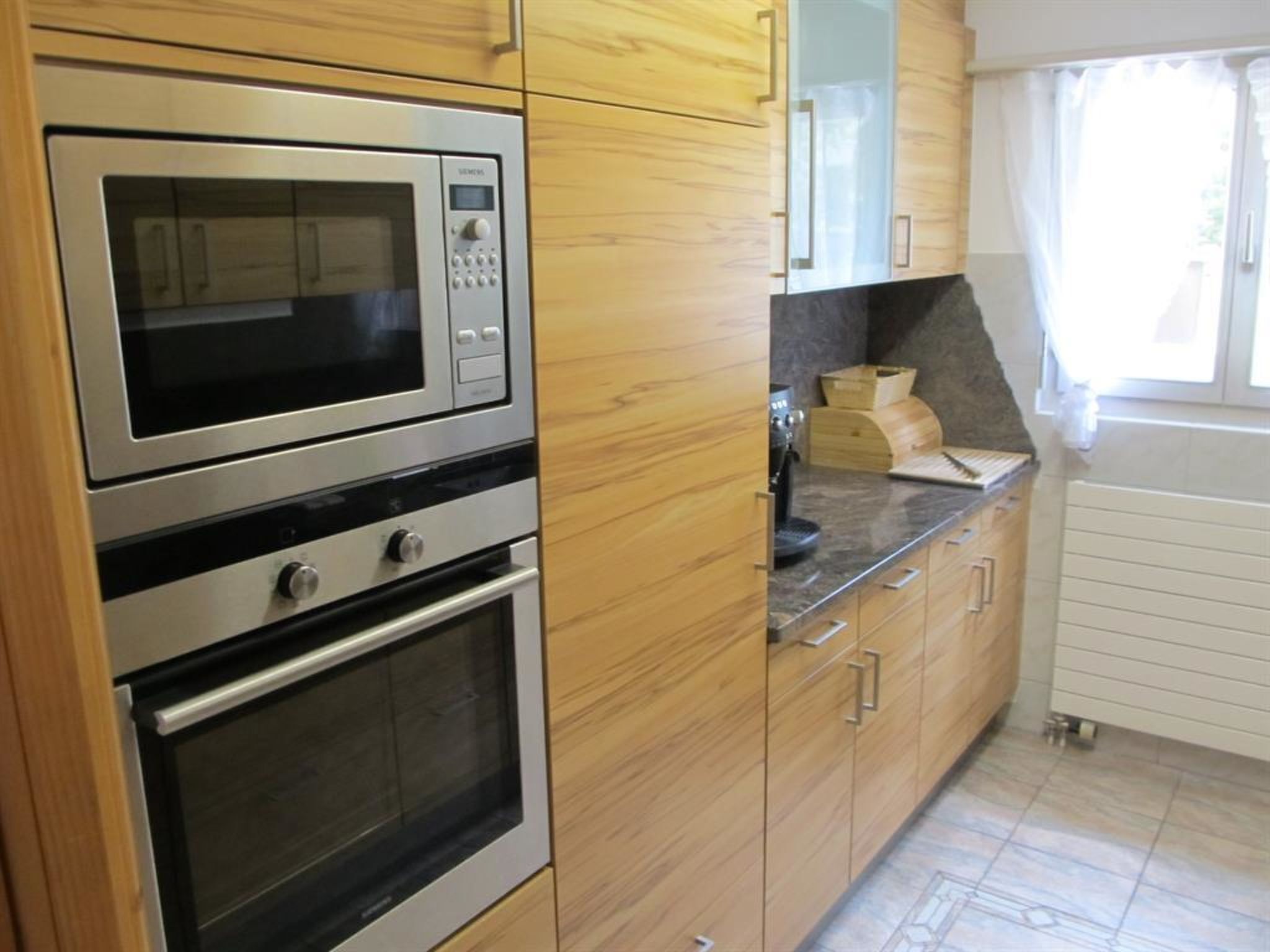 A kitchen with wooden cabinets, a built-in microwave, an oven, and a coffee maker.