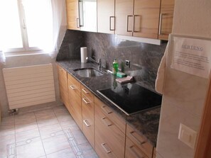 Eine Küche mit Holzschränken, einer schwarzen Arbeitsplatte, einem Spülbecken und einem Kühlschrank.