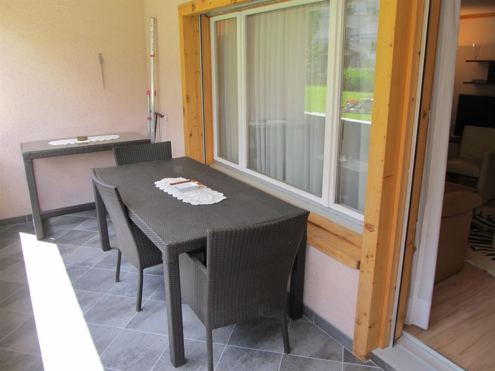 A dining area with a table and chairs, a window with blinds, and a door leading to another room.