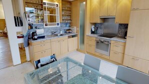 Uma cozinha moderna com armários de madeira, fogão de aço inoxidável e uma mesa de jantar de vidro.