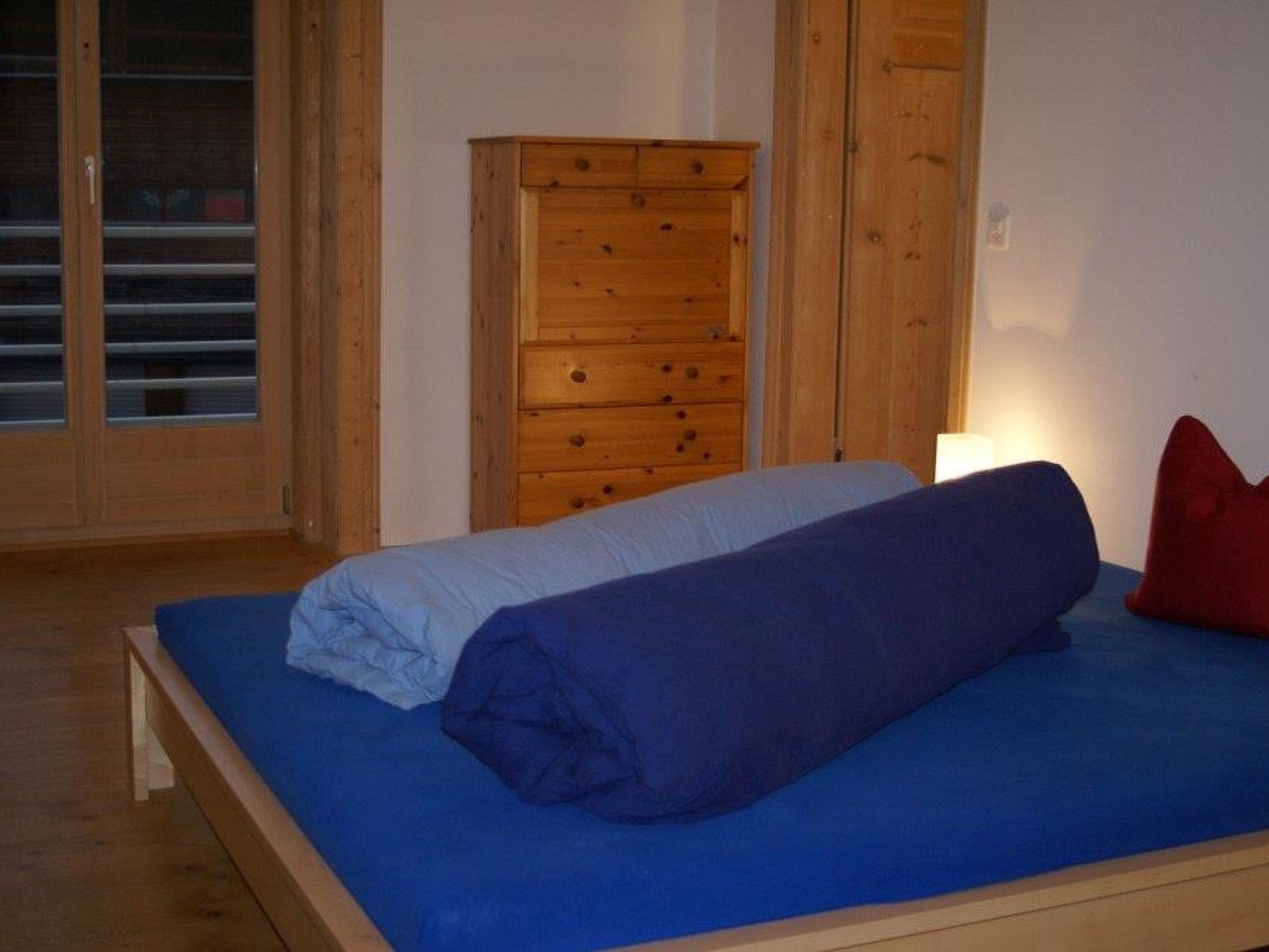 Una camera da letto con un letto, un armadio in legno e una finestra con persiane.