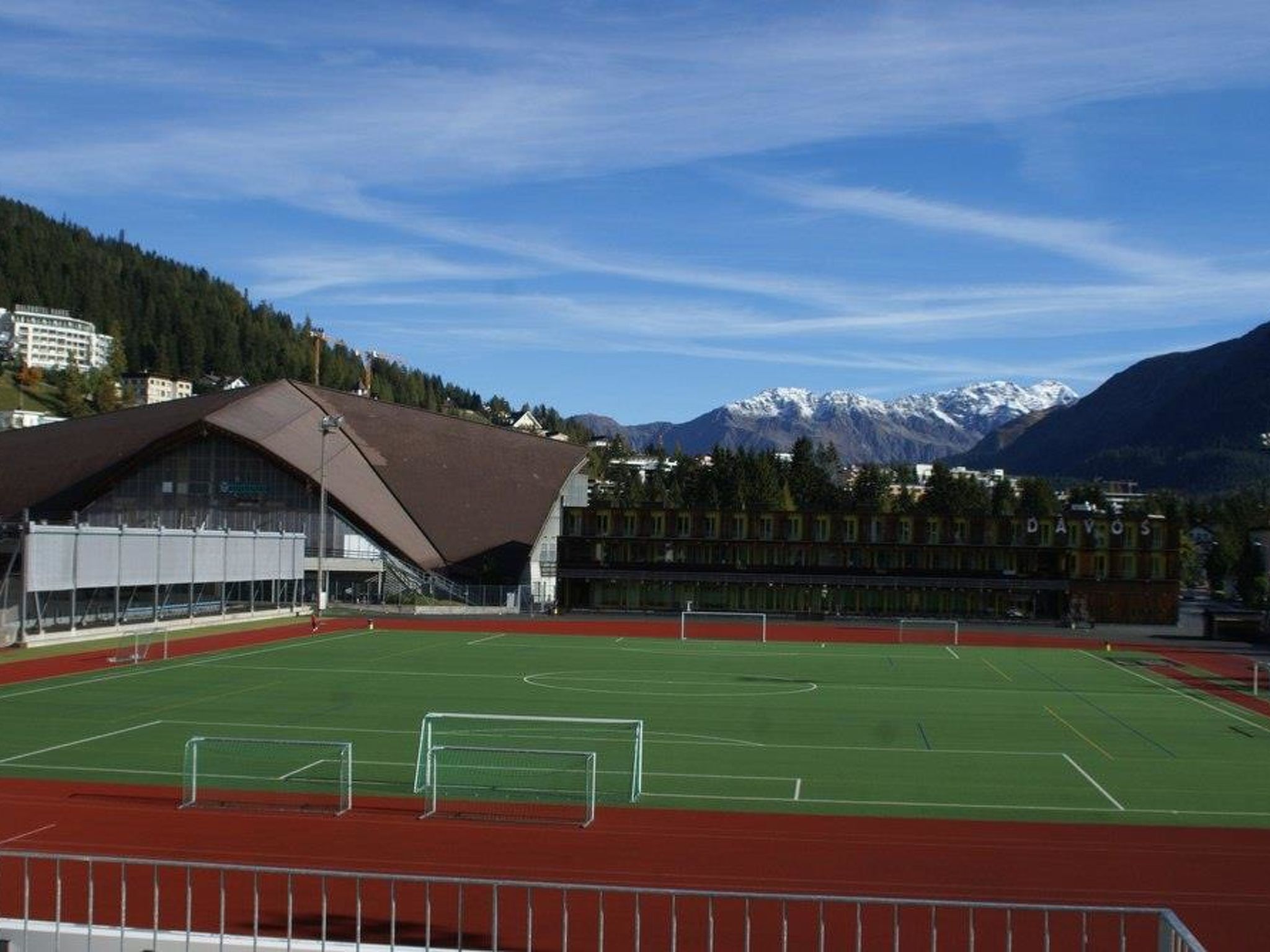 Un terrain de sport avec un bâtiment en arrière-plan et des montagnes.