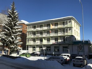 A multi-story building with balconies, parked cars, and a snow-covered tree. - Rialto 05 Appartement/Fewo, Dusche oder Bad, WC 4½-Zimmerwohnung by Interhome (Davos)