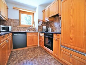 Una cocina con armarios de madera, microondas, lavavajillas y estufa.