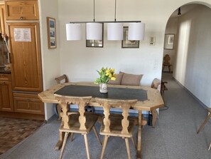 A dining area with a wooden table, chairs, and a vase with flowers. There are wall-mounted lights above the table. - Heimgut 37 Appartement/Fewo, Dusche oder Bad, WC 3½-Zimmerwohnung by Interhome (Davos)