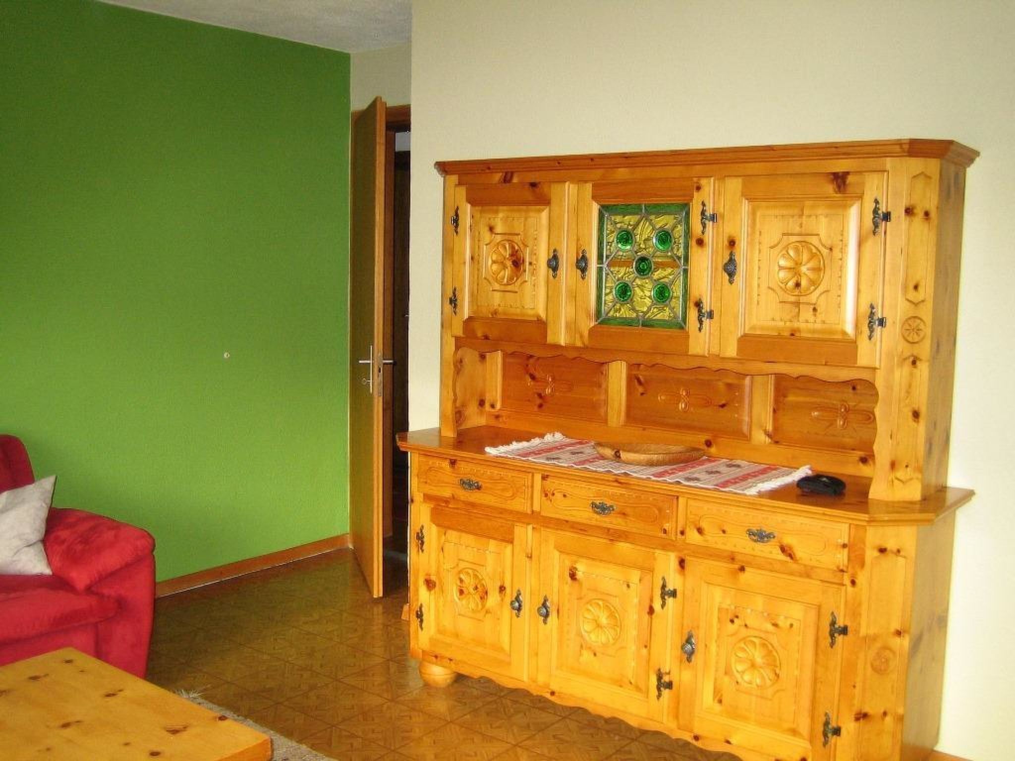 Un meuble en bois doté de plusieurs tiroirs et d’une porte en verre agrémentée de touches de vert.