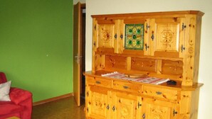 Un meuble en bois doté de plusieurs tiroirs et d’une porte en verre agrémentée de touches de vert.