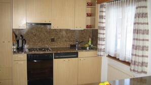 Une cuisine avec des meubles en bois, un plan de travail en granit, un lave-vaisselle et un panier à fruits.