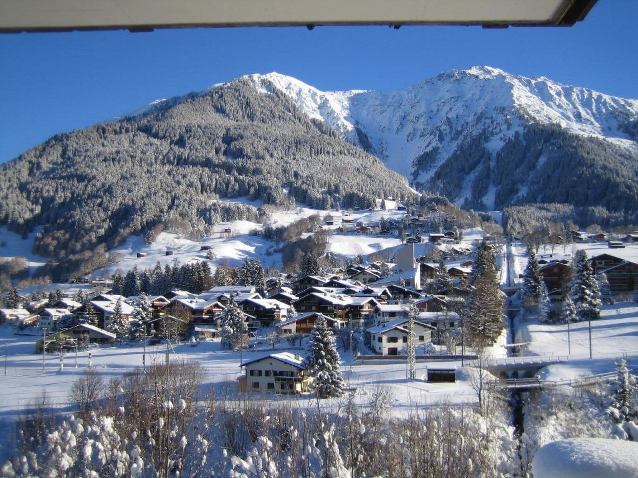 Ein verschneites Bergdorf mit Häusern und einer Kirche.