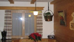 Un coin repas avec une table en bois, des bancs, une plante suspendue et une radio.
