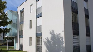 Moderni rakennus, jossa on useita ikkunoita ja parvekkeita, ja sen ympärillä on hyvin hoidettu nurmikko.
