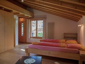 Habitación con estructura de madera, una cama, una mesa y vistas a edificios.
