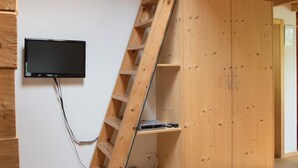 Una scala in legno conduce a un armadio con una televisione montata a parete.