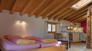 Una camera da letto con un letto di legno, una scrivania e un angolo cottura in un rifugio rustico.