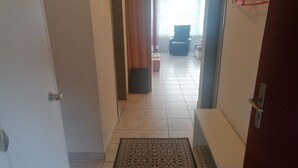En hall med en mönstrad matta, en stol och en soffa i bakgrunden.