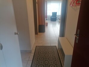 A hallway with a patterned rug, a chair, and a sofa in the background. - Talstrasse 22 App 34 Appartement/Fewo, Dusche oder Bad, WC 2½-Zimmerwohnung by Interhome (Davos)