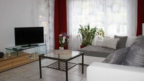 Ett vardagsrum med en TV, ett soffbord i glas, en soffa och en välkomstskylt.