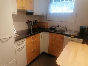 A kitchen with wooden cabinets, a black countertop, a sink, and a window with a view. - Talstrasse 22 App 34 Appartement/Fewo, Dusche oder Bad, WC 2½-Zimmerwohnung by Interhome (Davos)