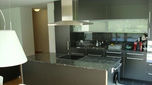 Una cucina moderna con isola centrale, mobili scuri e zona pranzo con tavolo e sedie.