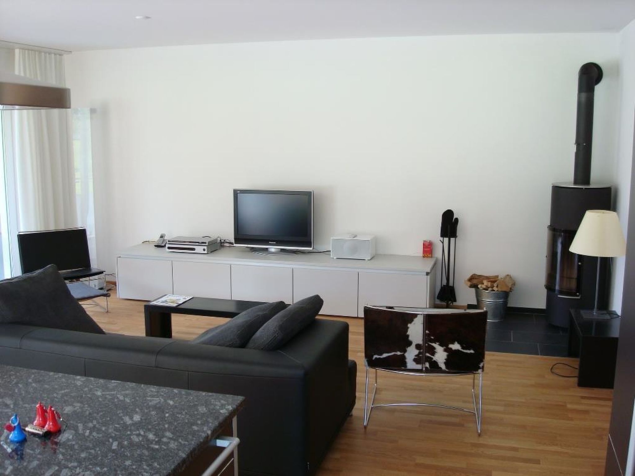 Ein modernes Wohnzimmer mit einer Couch, Fernseher, Unterhaltungseinheit und Kamin.