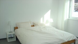 Una stanza semplice e pulita con un letto, un comodino con una lampada e una finestra.
