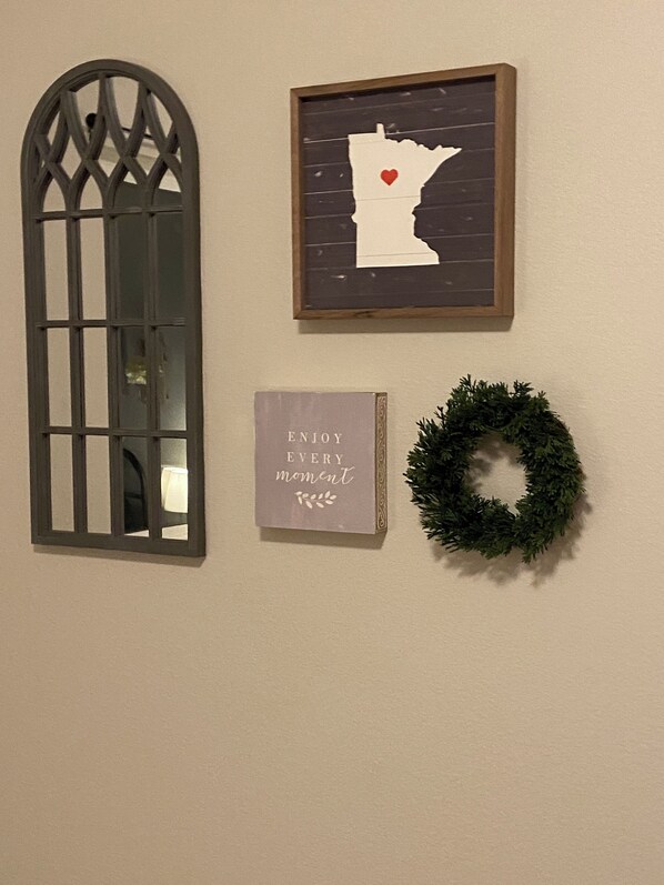 Una pared con un ventanal decorativo, un mapa enmarcado con un corazón y un letrero motivacional.