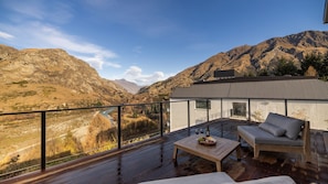 A modern outdoor deck with a view of a river and mountains.