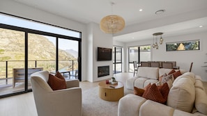 A spacious living room with a large window overlooking a mountainous landscape, a fireplace, and a dining area with a view.