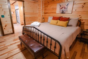 Une chambre à coucher de style cabane en bois, avec un lit, un banc et un tableau représentant un renard accroché au mur.