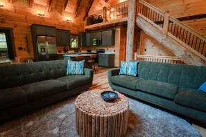 A wooden cabin interior with a living room, kitchen, and staircase. - Knotty Summit| Hocking Hills, Theater, Hot Tub (Logan)