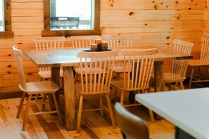 A wooden interior with a table and chairs, a window with a view, and a wooden floor.