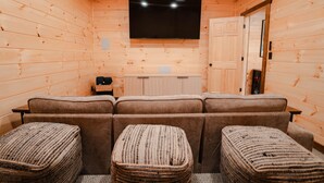 A wooden interior with a sofa, ottomans, a TV, and a cabinet. - Knotty Summit| Hocking Hills, Theater, Hot Tub (Logan)