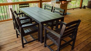 A wooden deck with a table and chairs, a grill, and a view of trees. - Knotty Summit| Hocking Hills, Theater, Hot Tub (Logan)