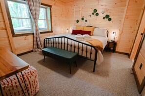 A wooden cabin bedroom with a bed, bench, and a small bedside table.