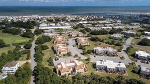 Vista aérea de una zona residencial costera con casas, caminos y una playa al fondo.