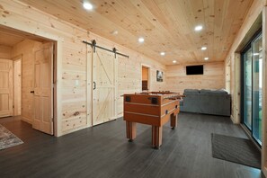 A wooden interior with a foosball table, a sofa, and a sliding door.