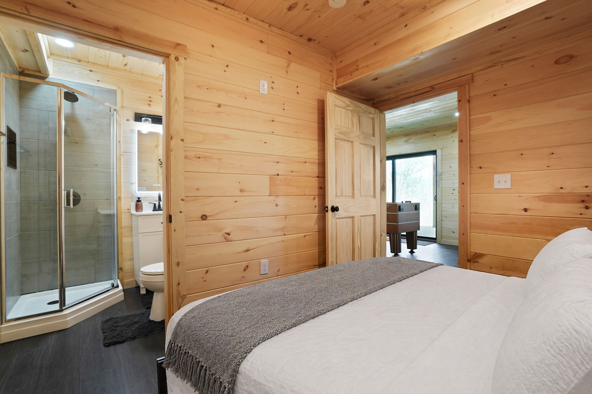 L'intérieur d'une cabane en bois, avec un lit, une douche et des toilettes.