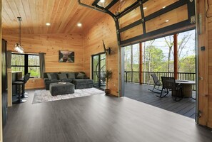 A spacious living area with a wooden ceiling, a sofa, a coffee table, and a view of the outdoors.