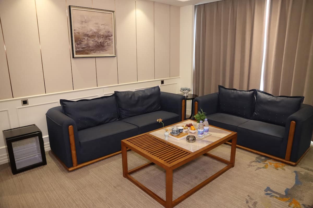 A living room with two dark sofas, a wooden coffee table, a small side table with a vase and a plant, and a radiator.