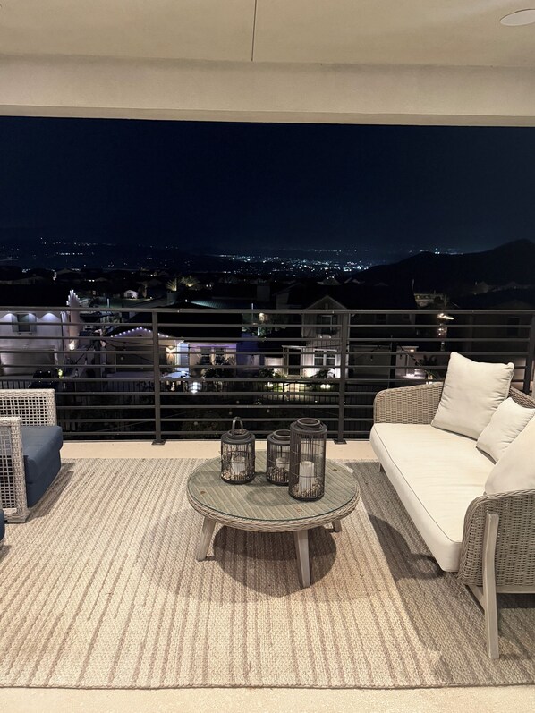 A balcony with a sofa, a round table, and three lanterns.
