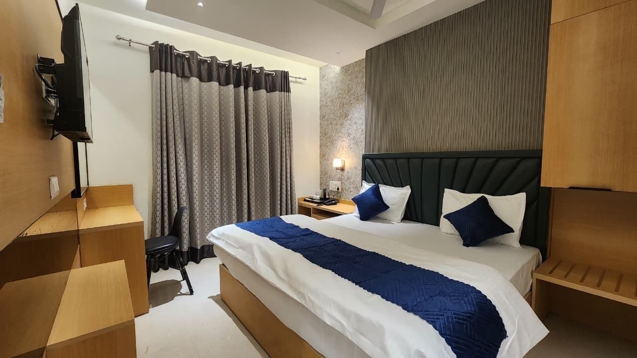 A modern hotel room with a large bed, a television, a nightstand, and a shower curtain.
