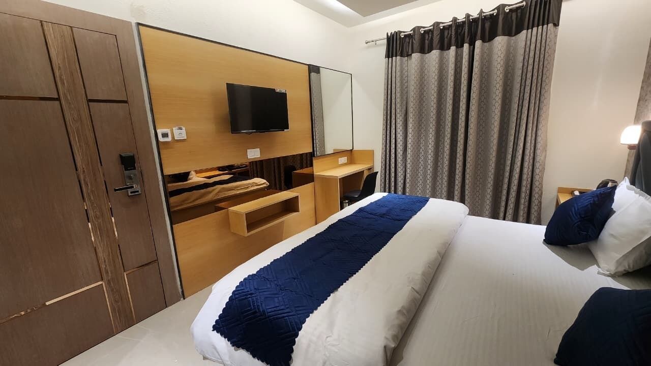 Hotellihuone, jossa on sänky, televisio, työpöytä ja vaatekaappi.