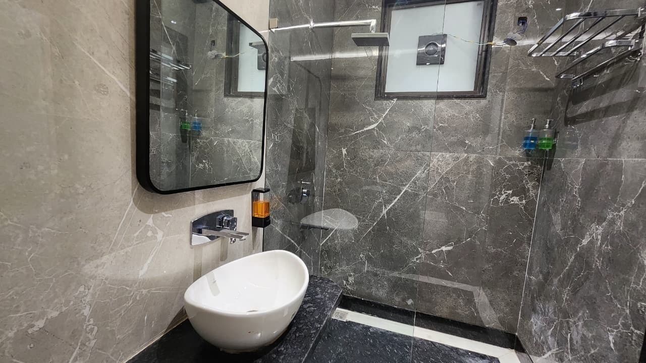 A bathroom with a white sink, a mirror, a shower, and a towel rack.